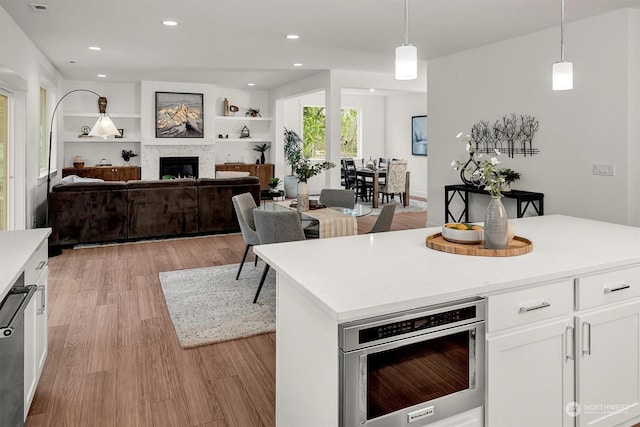 kitchen with decorative light fixtures, white cabinetry, built in features, and a kitchen island