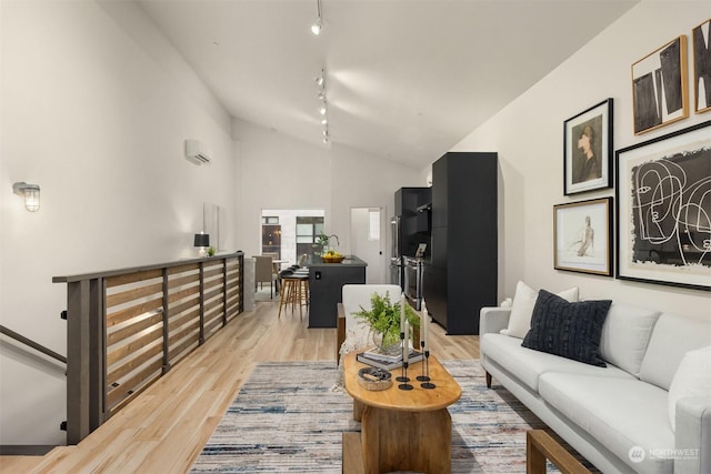 living room featuring lofted ceiling, rail lighting, and light hardwood / wood-style floors
