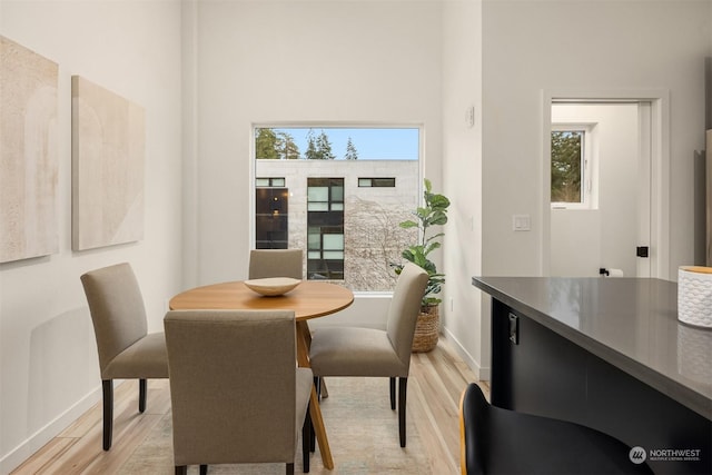 dining area featuring light hardwood / wood-style floors and a high ceiling