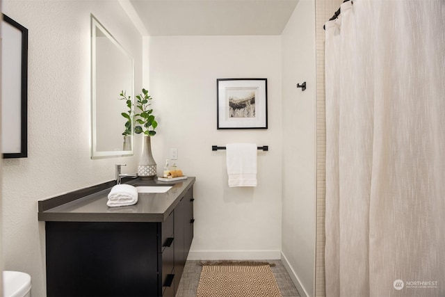bathroom with toilet, vanity, and tile patterned flooring