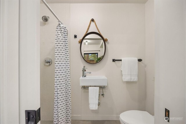 bathroom with toilet, sink, and curtained shower