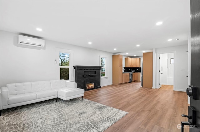 living room featuring an AC wall unit, light wood-type flooring, and a fireplace