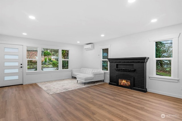 unfurnished living room featuring light hardwood / wood-style floors, plenty of natural light, a wall unit AC, and a fireplace