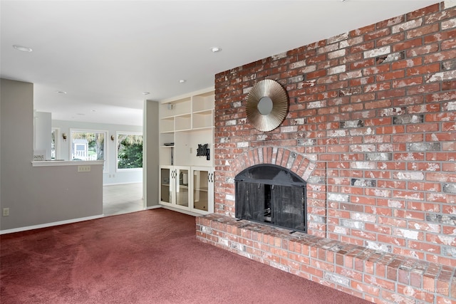 unfurnished living room with built in shelves, a fireplace, and carpet flooring