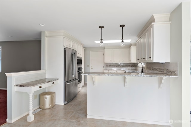 kitchen featuring decorative light fixtures, white cabinets, a kitchen bar, and kitchen peninsula