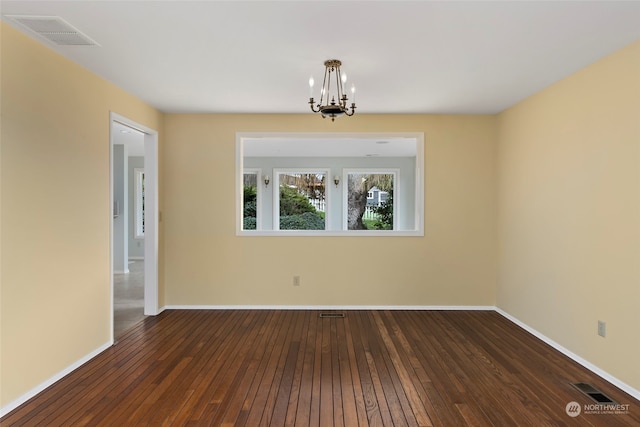 spare room with dark wood-type flooring and a chandelier