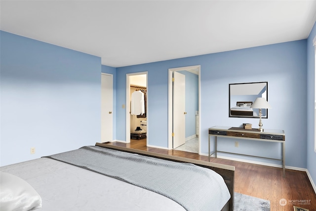 bedroom featuring wood-type flooring, a spacious closet, ensuite bathroom, and a closet