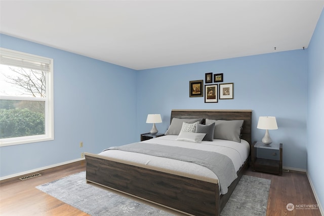 bedroom with multiple windows and dark hardwood / wood-style floors