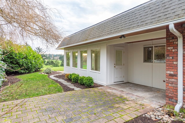 view of exterior entry featuring a yard and a patio area