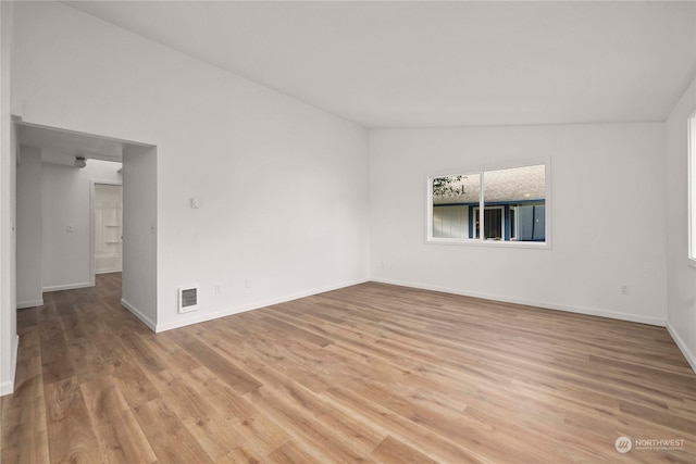 unfurnished room featuring lofted ceiling and light wood-type flooring