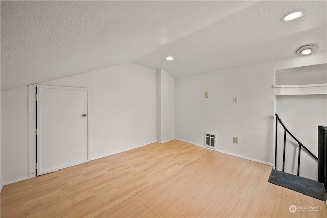 bonus room featuring a textured ceiling, lofted ceiling, and wood-type flooring