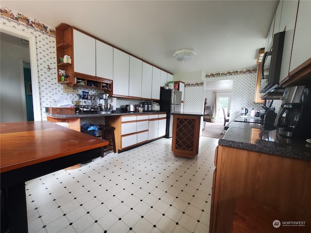 kitchen with white cabinetry and stainless steel fridge