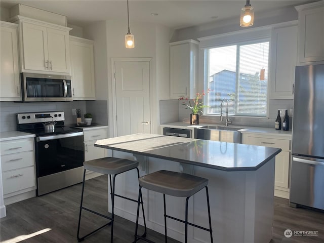 kitchen featuring sink, appliances with stainless steel finishes, tasteful backsplash, white cabinets, and a kitchen island