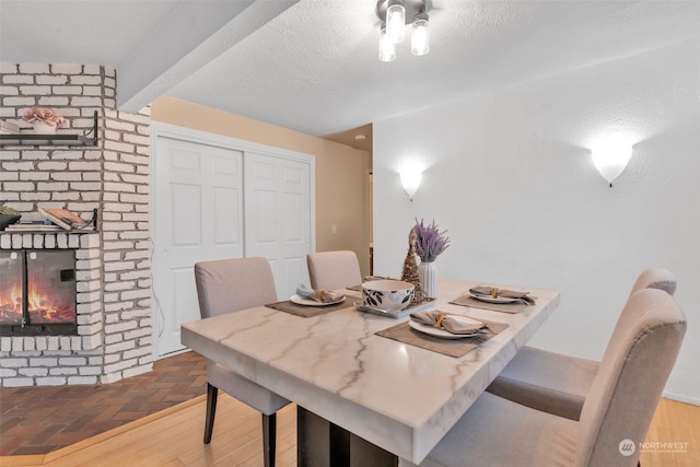 dining room with a textured ceiling, beamed ceiling, and a fireplace