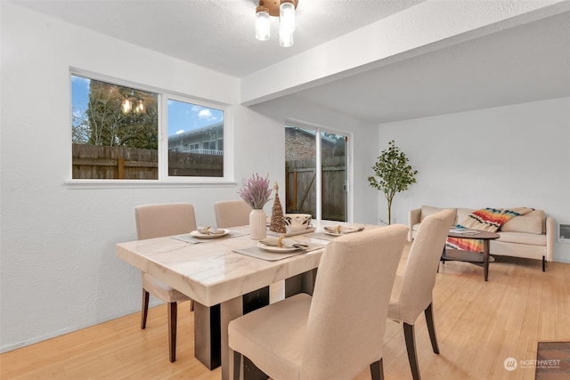 dining room with beam ceiling and light wood-type flooring