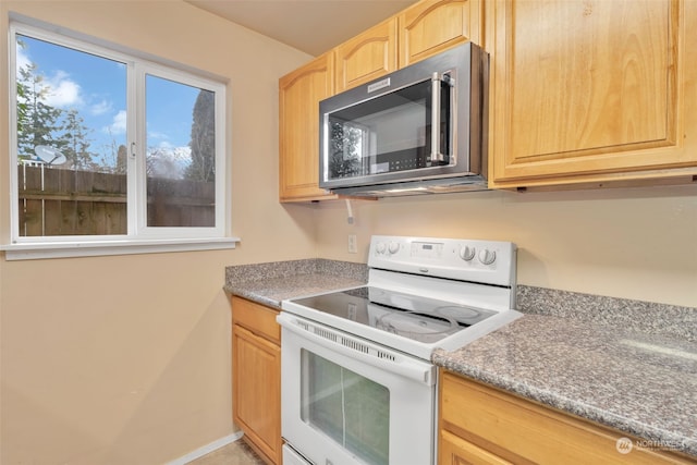 kitchen featuring light brown cabinets and white electric stove