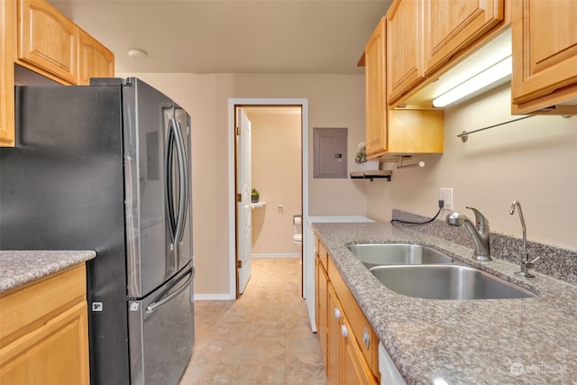 kitchen featuring light tile patterned floors, light brown cabinets, stainless steel refrigerator, electric panel, and sink