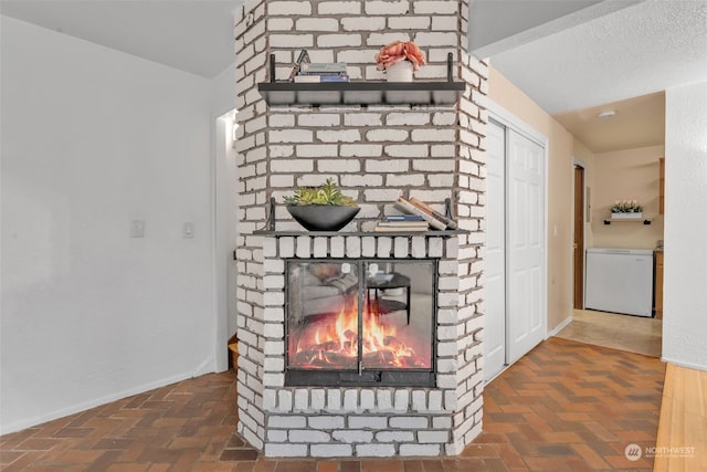 interior details with a brick fireplace, a textured ceiling, and dishwasher