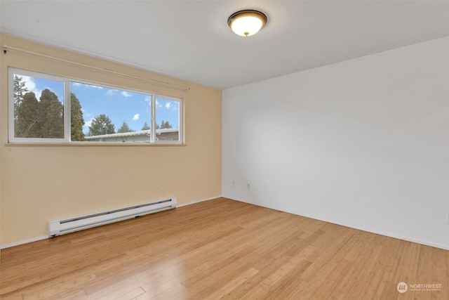 spare room featuring a baseboard heating unit and light hardwood / wood-style floors