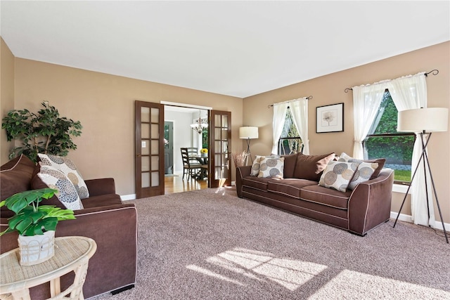 carpeted living room featuring french doors and a notable chandelier