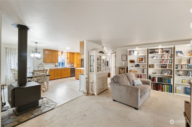 carpeted living room with a wood stove and sink