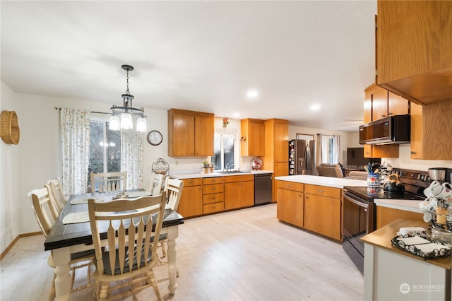 kitchen featuring appliances with stainless steel finishes, decorative light fixtures, sink, a notable chandelier, and light hardwood / wood-style flooring