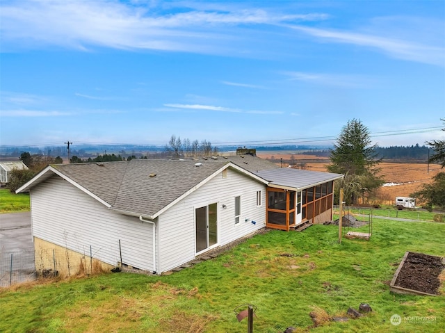 rear view of house with a yard and a sunroom