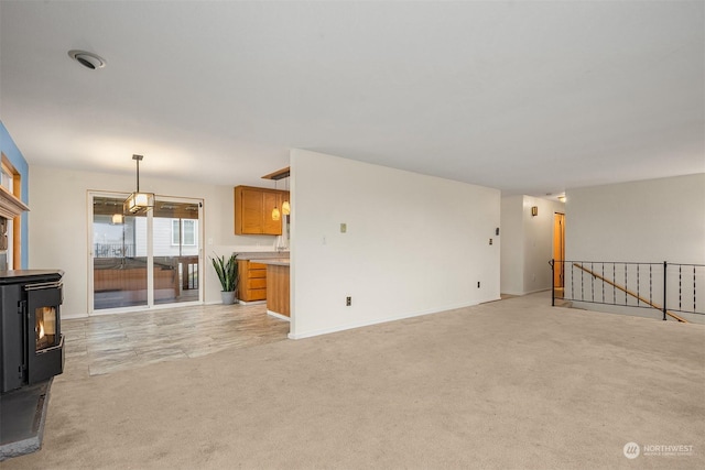 unfurnished living room featuring light carpet and a wood stove