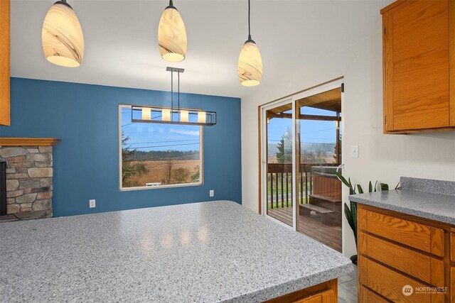 kitchen featuring decorative light fixtures, a healthy amount of sunlight, and a stone fireplace