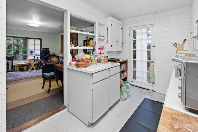 kitchen with plenty of natural light, white cabinetry, and wood walls