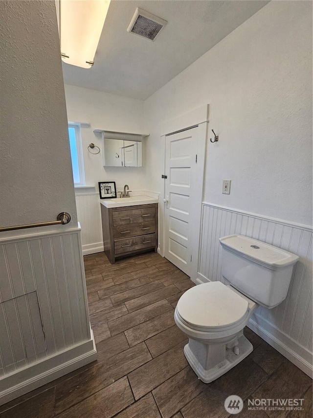 1651 S 35th St, Tacoma, WA 98418 - bathroom with wood finished floors, vanity, toilet, and a wainscoted wall