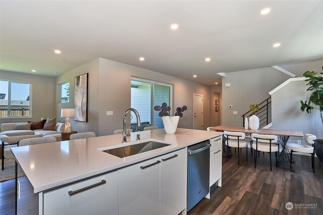 kitchen with white cabinets, an island with sink, open floor plan, light countertops, and a sink