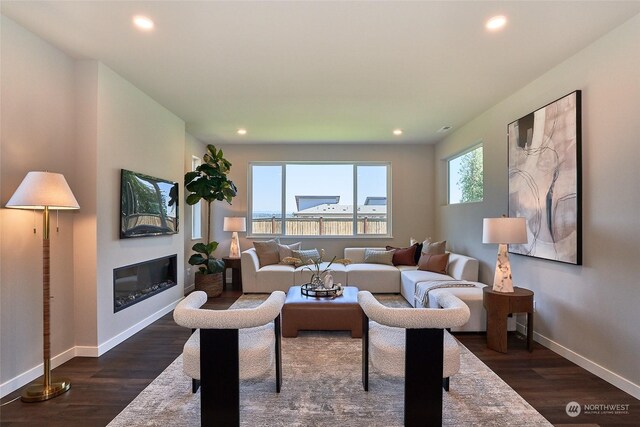 living area with dark wood-type flooring, recessed lighting, a glass covered fireplace, and baseboards