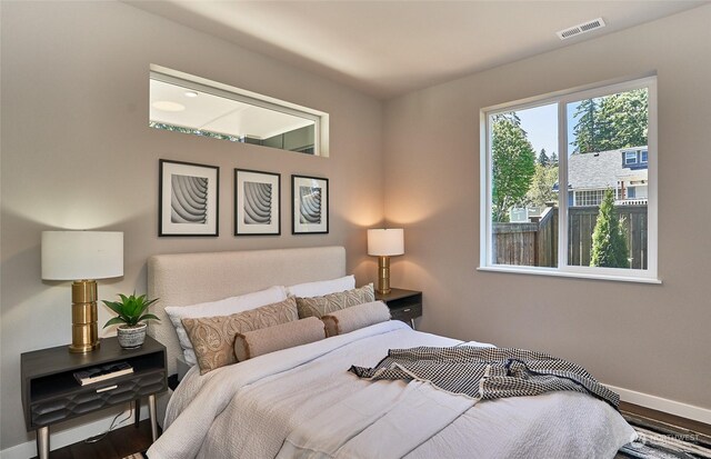 bedroom with visible vents, baseboards, and wood finished floors