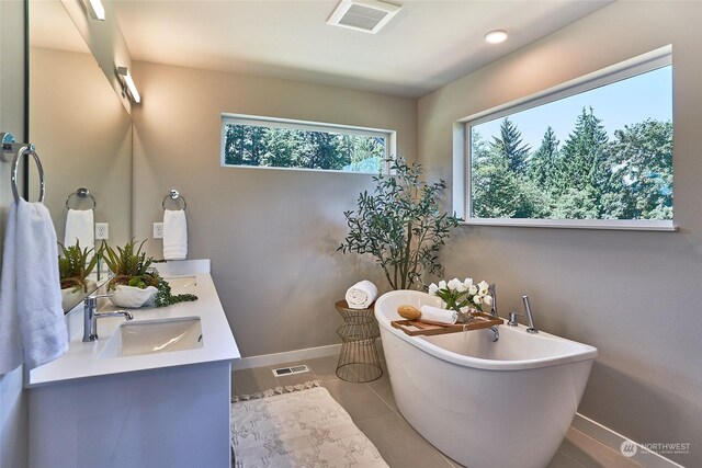 full bath with visible vents, a freestanding bath, a sink, baseboards, and tile patterned floors