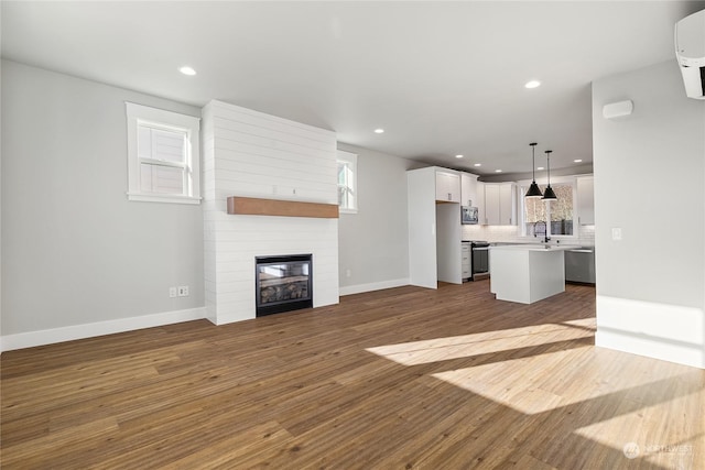 unfurnished living room featuring dark wood-type flooring, sink, and a large fireplace