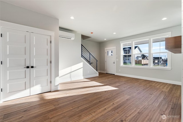 foyer entrance with light hardwood / wood-style flooring and a wall unit AC