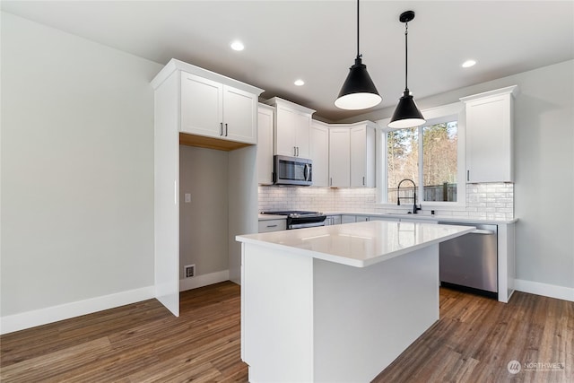 kitchen featuring stainless steel appliances, a center island, sink, and white cabinets