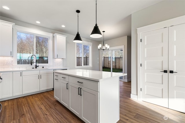 kitchen with sink, a center island, tasteful backsplash, white cabinets, and decorative light fixtures