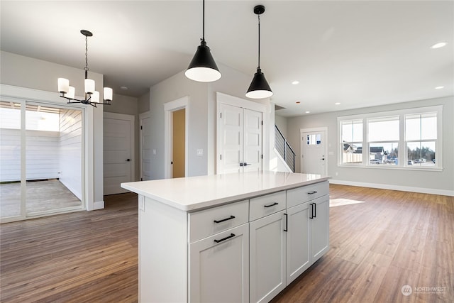 kitchen with hanging light fixtures, dark hardwood / wood-style floors, white cabinets, and a kitchen island