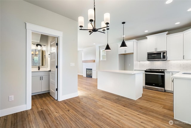 kitchen with white cabinetry, appliances with stainless steel finishes, decorative light fixtures, and a center island