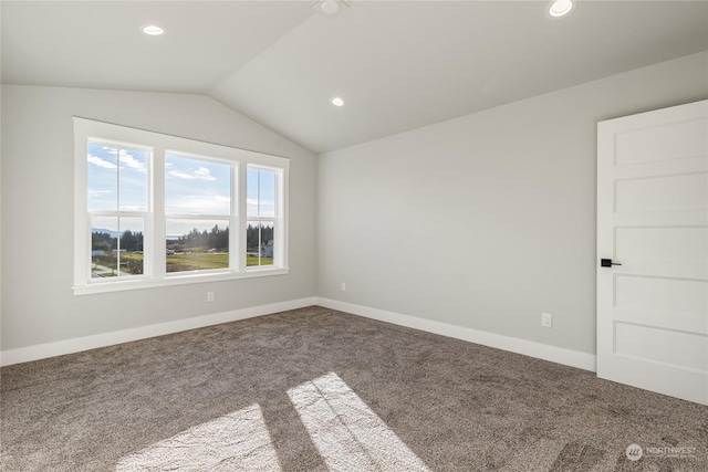 carpeted spare room featuring vaulted ceiling