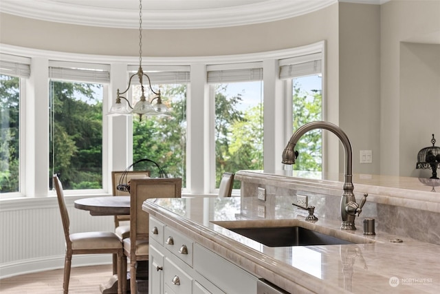 interior space with light stone countertops, decorative light fixtures, white cabinetry, sink, and a notable chandelier