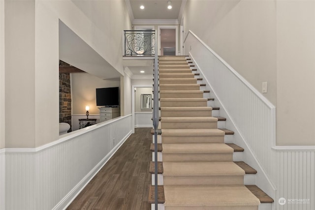 staircase featuring hardwood / wood-style floors, crown molding, and a towering ceiling