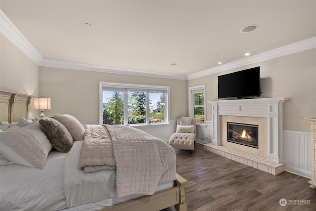 bedroom featuring dark wood-type flooring, a tile fireplace, and crown molding