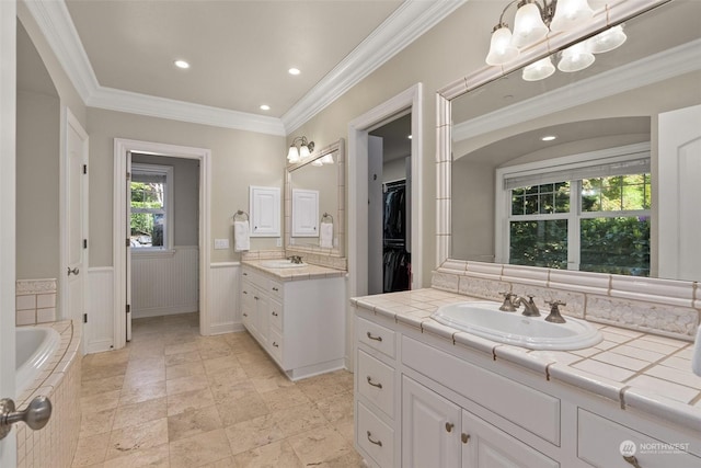 bathroom featuring vanity, ornamental molding, and a bath