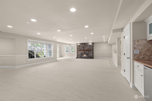 unfurnished living room with light colored carpet and a fireplace