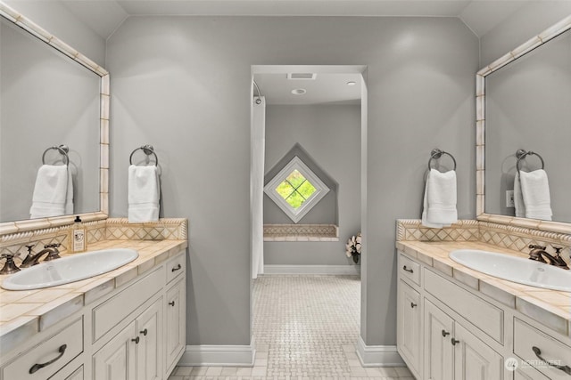 bathroom featuring vaulted ceiling, tile patterned flooring, backsplash, and vanity