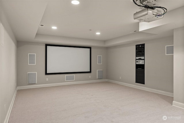 carpeted cinema room featuring a raised ceiling