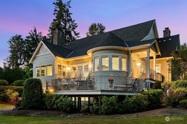 back house at dusk with a balcony